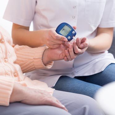 Home Health Care Nurse checking blood sugar level